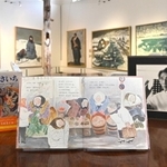 復刊された絵本「あさいち」。作者大石可久也さんの写真（右）と並ぶ＝アート山大石可久也美術館