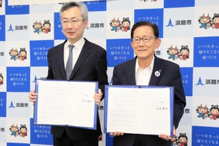 協定書を手にする神戸大学医学部付属病院の眞庭謙昌院長（左）と門康彦市長＝淡路市役所