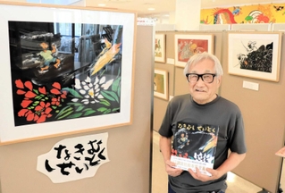 「なきむしせいとく」の原画のそばで絵本を持つ田島征彦さん＝淡路市富島
