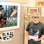 「なきむしせいとく」の原画のそばで絵本を持つ田島征彦さん＝淡路市富島