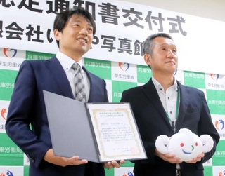 認定通知書を受け取るいせや写真館の西田晃三社長（左）とハローワーク洲本の砂川佳之所長＝県洲本総合庁舎