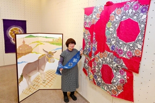 本年度の兵庫工芸展で大賞に輝いた振り袖（右）や、昨年度の日展で入選したロバのびょうぶ絵などの作品と中来田万里さん＝サンシャインホール