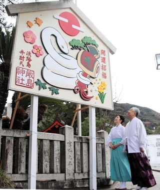 白蛇と打ち出の小づちが描かれたジャンボ絵馬を見上げる浦上雅史宮司（右）と浦上直子禰宜＝厳島神社