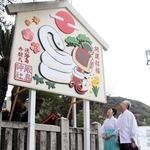 白蛇と打ち出の小づちが描かれたジャンボ絵馬を見上げる浦上雅史宮司（右）と浦上直子禰宜＝厳島神社