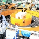 既存の台船で海底ケーブルを巻いたターンテーブルを背に語る関勝社長＝淡路市生穂新島