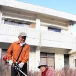今も残る鉄筋の家の前で、伸びた雑草を刈り取る田中益也さん（左）、千鶴子さん＝淡路市野島蟇浦