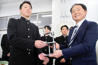 完成した線香作りの機械をパルシェ香りの館の葉坂光則さん（右）とともに手にする洲本実業高の生徒＝洲本実業高校