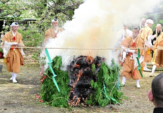 炎を上げる柴燈に護摩を投げ込む僧侶＝神本寺