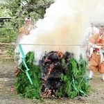 炎を上げる柴燈に護摩を投げ込む僧侶＝神本寺