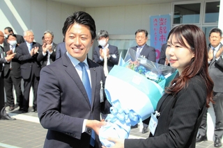 拍手で迎える職員の前で花束を受け取る戸田敦大市長＝淡路市役所
