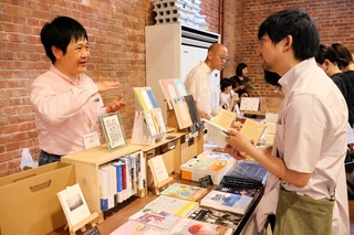 来場者に本の説明をする主催者の鈴木遊さん（左）＝洲本市塩屋１