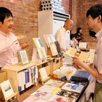 来場者に本の説明をする主催者の鈴木遊さん（左）＝洲本市塩屋１