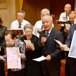 山口さんの遺影などを手に「サライ」を合唱する出席者たち＝南あわじ市阿那賀