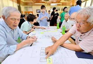 避難所の図面を広げ、避難者への対応などを考える参加者＝長沢エコセンター