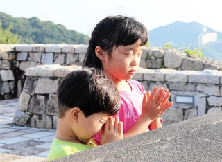 今年の終戦の日、戦没学徒を慰霊する塔の前で子どもが手を合わせていた＝南あわじ市阿万塩屋町