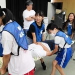 竹の棒と毛布で作った担架で人を運ぶ児童ら＝南あわじ市役所