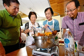 ライフラインの停止を想定した薄暗い部屋でパッククッキングに取り組む参加者＝長沢エコセンター