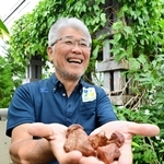 ヒスイカズラの種子を手に満面の笑顔を見せる石田均ディレクター＝あわじグリーン館