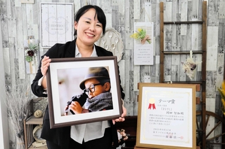 「今後の自信に」と富士フイルム営業写真コンテストで入賞した作品を手に笑顔の岡田智加さん＝洲本市海岸通２