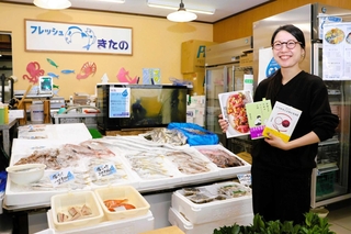 実家の鮮魚店で書店を兼業する北野洋子さん。兄と姉が手がけた本や魚の料理本を手に「地域の人に読書の喜びを」と話す＝南あわじ市志知佐礼尾