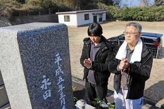 震災発生の１７日、里海さんが眠る墓前で手を合わせる永田守さん（右）と長男の直之さん＝淡路市富島