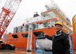 新造の海底ケーブル敷設台船「あわじ」の前で「海の仕事の魅力を知ってほしい」と話す関勝社長＝淡路市生穂新島