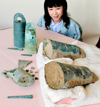 発見当時の松帆銅鐸。大きい銅鐸に小さい銅鐸をはめ込んだ「入れ子状態」で、棒状の「舌」とセットで埋められていた（２０１５年５月１９日）