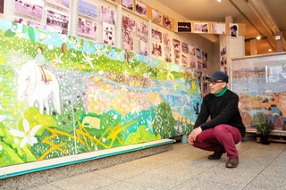 洲本の町をモチーフにした作品の前で「出会った人々を思いながら描いた」と話す山田宗宏さん＝洲本市本町８