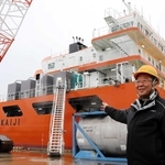 新造の海底ケーブル敷設台船「あわじ」の前で「海の仕事の魅力を知ってほしい」と話す関勝社長＝淡路市生穂新島