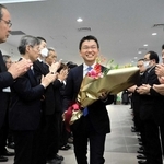 花束を受け取り、職員らに拍手で迎えられる吉平敏孝市長＝洲本市役所