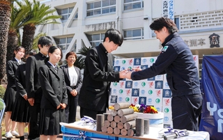 植田峻正専務（右）から鉄の丸棒を受け取る生徒ら＝洲本実業高校