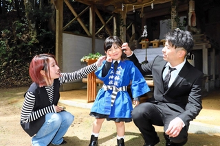 「当人」を務めて笑顔を見せる保地茉衣莉ちゃん（中央）と両親の貴文さん、愛葵さん＝淡路市小田