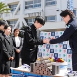 植田峻正専務（右）から鉄の丸棒を受け取る生徒ら＝洲本実業高校