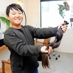 ヘアドネーションのためカットした約５０センチの髪の毛を手に「伸ばしてきて良かった」と笑顔を見せる東原祥真さん＝洲本市池内