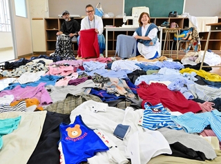 たくさんの古着を前に、リメークへのチャレンジを呼びかける（右から）清水かなよさん、増見喜一朗社長ら＝淡路市江井