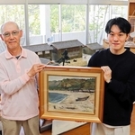 橋本勇次さん（左）から江井の海浜を描いた油絵を受け取る、ｅｉ－ｔｏスタッフの矢野剛史さん＝淡路市江井