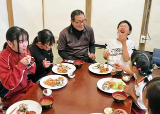 堂本秀幸さん（中央）が手作りした食事に笑顔を見せる子どもら＝南あわじ市八木鳥井