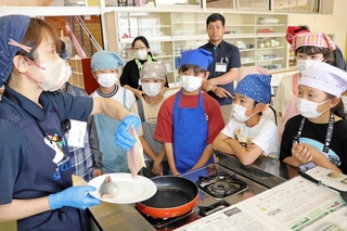 講師の柏木裕子さん（左）にアジのソテーの作り方を教わる５年生＝浦小学校