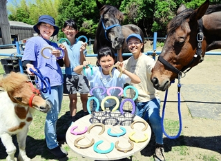 蹄鉄をペイントし、アートグッズに生まれ変わらせた山下勉さん一家。引退後の馬の活躍の場づくりに役立てる＝洲本市五色町鳥飼浦