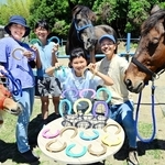 蹄鉄をペイントし、アートグッズに生まれ変わらせた山下勉さん一家。引退後の馬の活躍の場づくりに役立てる＝洲本市五色町鳥飼浦