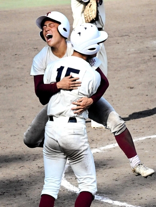 延長１０回表津名２死一、三塁、川端理央選手の勝ち越し打で一塁から生還し、チームメートに抱きついて喜ぶ内田有哉選手＝姫路市のウインク球場