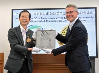 姉妹都市提携３０周年記念の瓦を手にする守本憲弘市長（左）とジェフリー・ヘーゼル市長＝南あわじ市役所