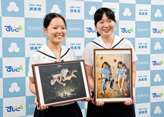出品作の写真を手にする太田和花さん（左）と土居叶乃さん＝洲本市役所