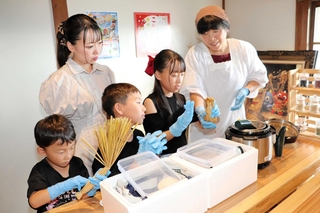 長澤納豆店の紺野恵子さん（右端）に教わり、「こおに納豆」を作る親子＝淡路市長沢