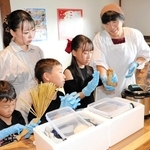 長澤納豆店の紺野恵子さん（右端）に教わり、「こおに納豆」を作る親子＝淡路市長沢