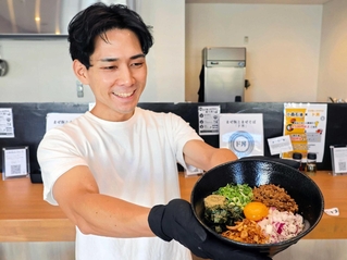 看板メニューのまぜそばの丼を手にする曽我亨明さん。豊富なトッピングが売りだ＝洲本市本町４