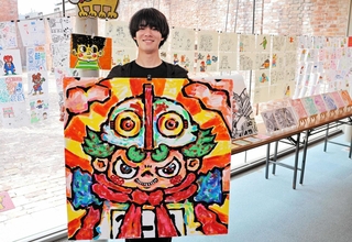 最新作を手に「カラフルな空間を楽しんで」と話す冨永大和さん＝洲本市塩屋１