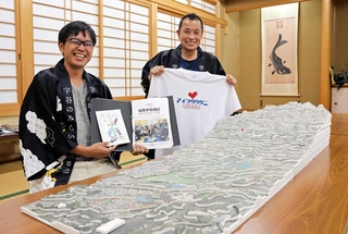 宇谷の立体地図を前に「集落の教科書」やＴシャツを手にする三崎雄太さん（左）と堂原克太さん＝洲本市五色町鮎原宇谷