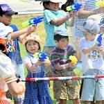 放水に負けず、水鉄砲で的を狙う子どもら＝淡路市塩田新島