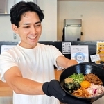 看板メニューのまぜそばの丼を手にする曽我亨明さん。豊富なトッピングが売りだ＝洲本市本町４